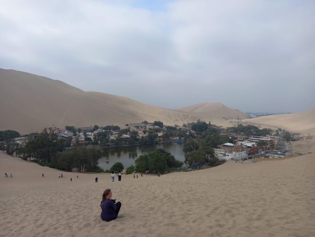 Yo sentada frente al oasis de Huacachina