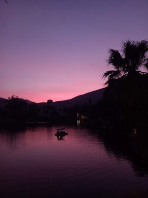 Foto del lago del oasis de Huacachina al atardecer, con cielo rosado.