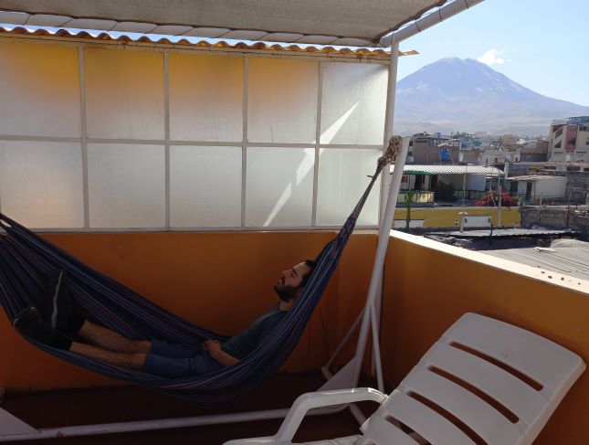 Foto de Josu tumbado en una hamaca en la azotea de nuestro hostal, al fondo se aprecia el volcán Misti.